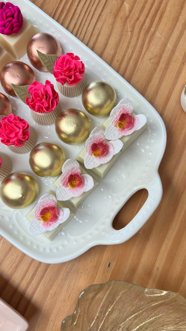 Bandeja com doces dourados, cravos pink e orquídeas de açúcar