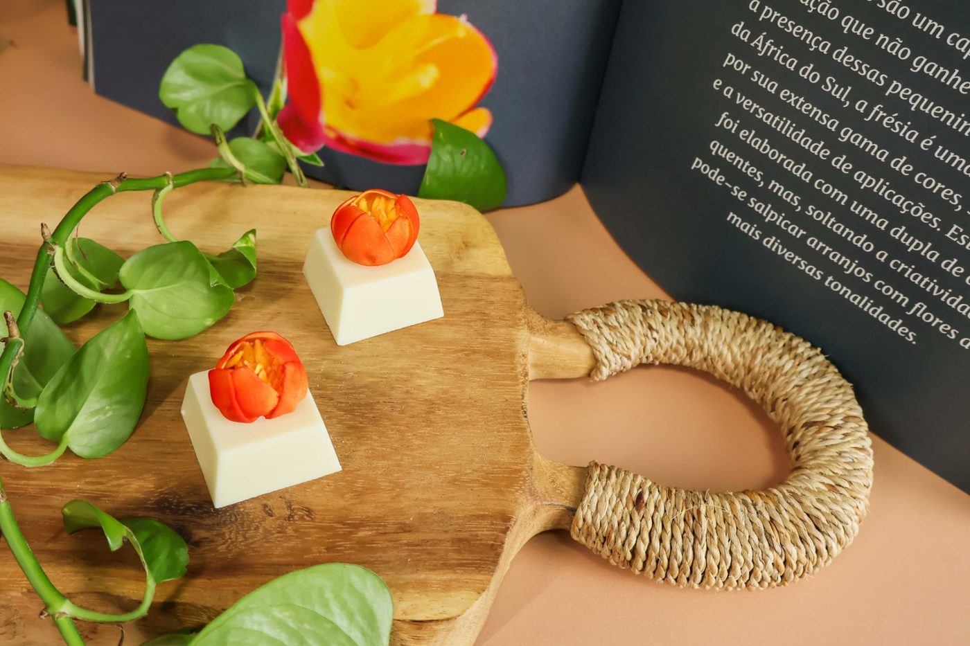 Doces finos com flores laranjas de açúcar sobre tábua de madeira